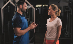 Ein Mann und eine Frau unterhalten sich in einem Fitnessstudio.
