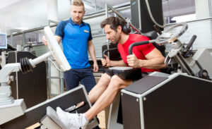 Ein Mann trainiert auf einem stationären Fahrrad in einem Fitnessstudio.