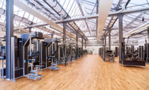 Ein Fitnessstudio mit einem großen Raum, der mit zahlreichen Trainingsgeräten ausgestattet ist.