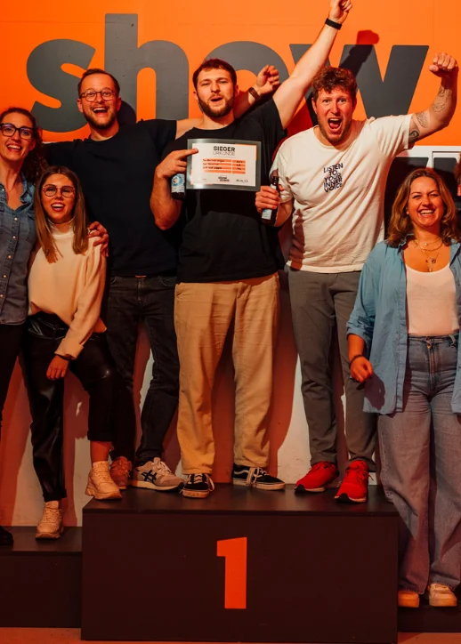 Die Gewinner des Wettbewerbs "Your Showdown" stehen stolz auf der Bühne und halten ihre Trophäen in den Händen.