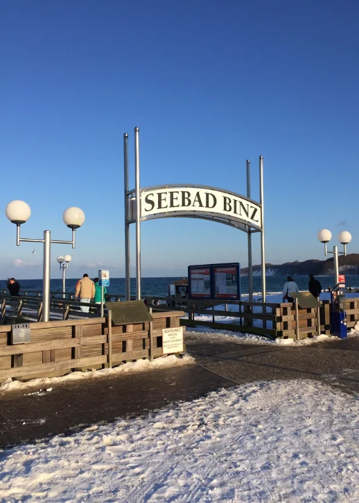 Schneebedeckter Eingang zum Ufer in Ostseebad Binz, der eine friedliche Winterlandschaft zeigt.