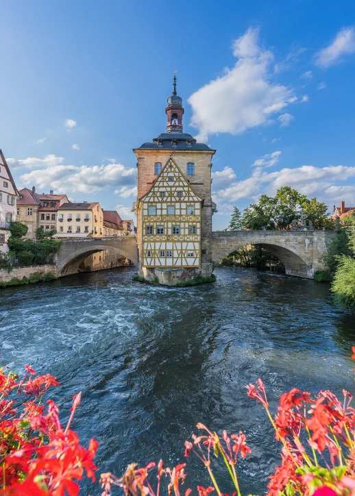 Blick auf die Altstadt von Bamberg, Deutschland, mit einem Fluss und blühenden Blumen.
