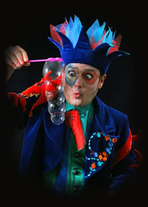 Ein Mann in einem blauen und roten Kostüm hält Blasen während der Unterwasser-Bubble-Show in Berlin.