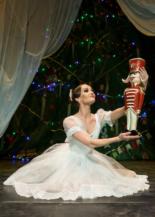 Im Stage Theater Berlin steht eine Frau in einem weißen Ballettkleid, mit einem Nussknacker in der Hand.