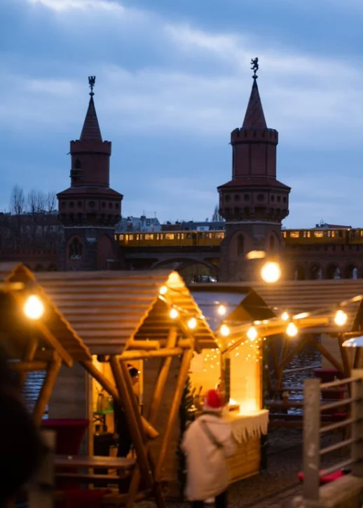 Gemütliche Stadtstraße mit Tischen und Stühlen, ideal für den Besuch des Weihnachtsmarkts an der Spree.