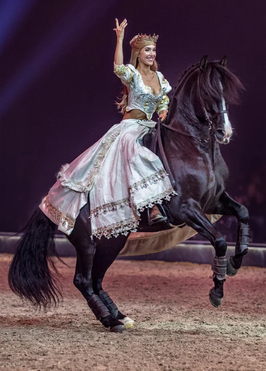 Eine Frau in einem Kleid reitet ein Pferd in einer Arena während der CAVALLUNA-Show in Berlin.