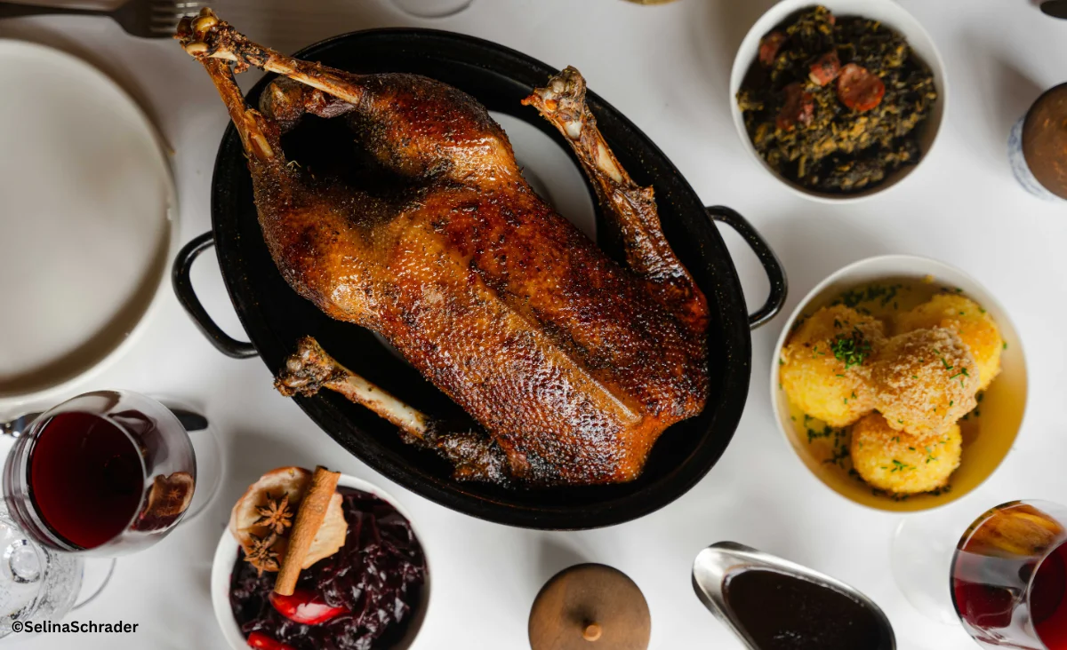 Ein gebratener Entenbraten auf einem Tisch, umgeben von verschiedenen Gerichten aus der Ganymed Brasserie.