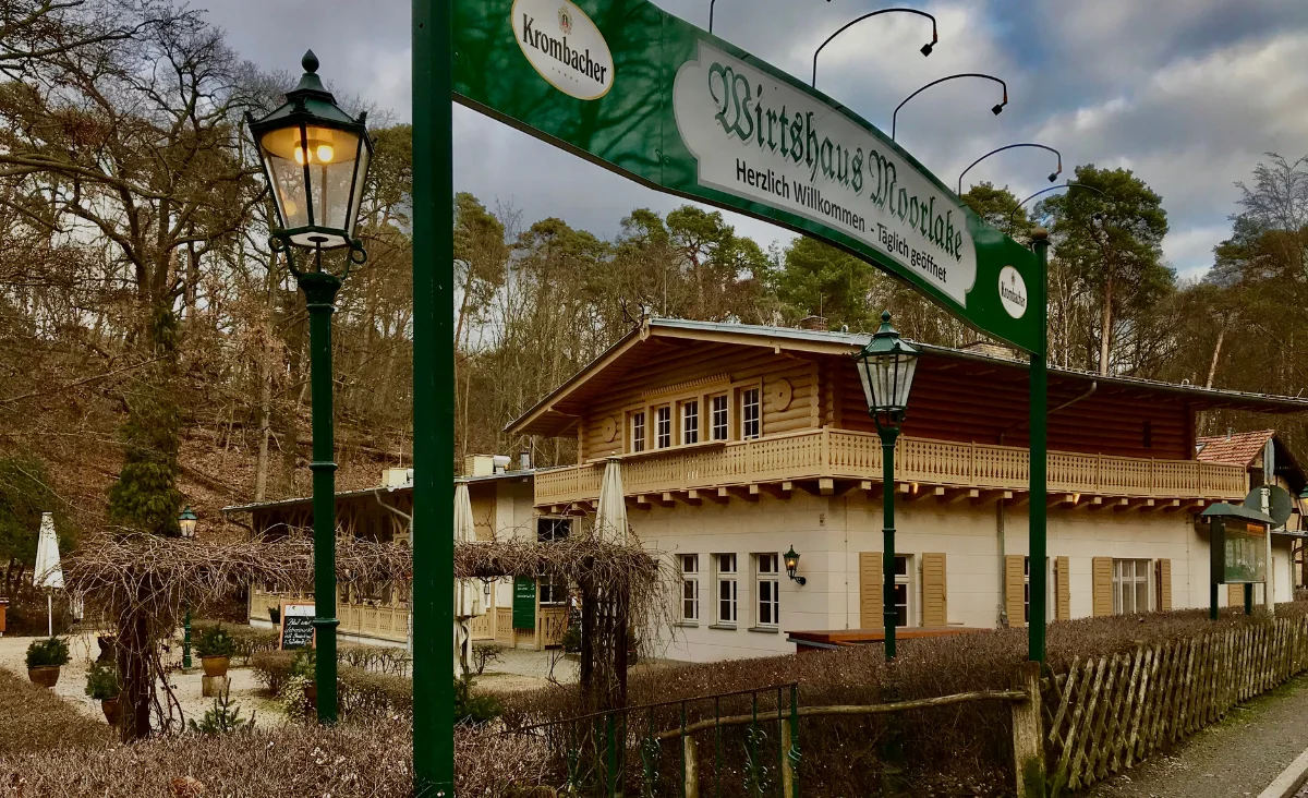 Schild in Grün und Weiß, welches Restaurant Historisches Wirtshaus Moorlake anzeigt.