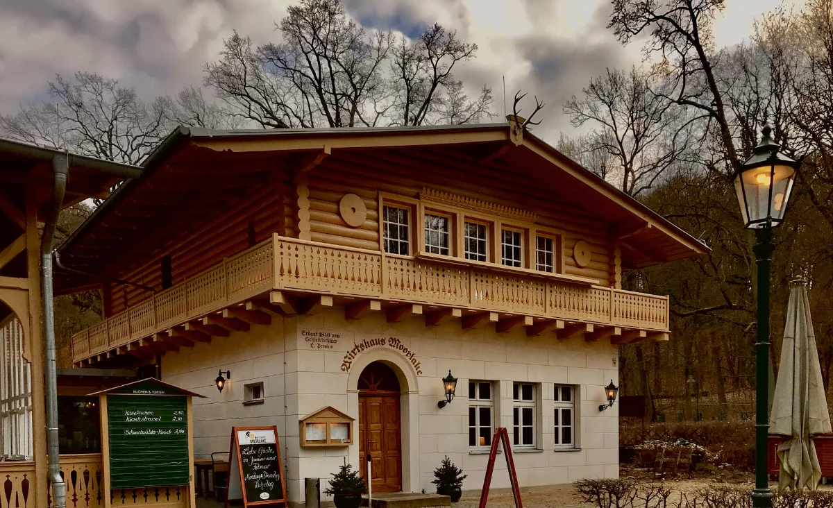 Gemütliches Holzhaus mit Balkon und einem Schild für das Restaurant Historisches Wirtshaus Moorlake.