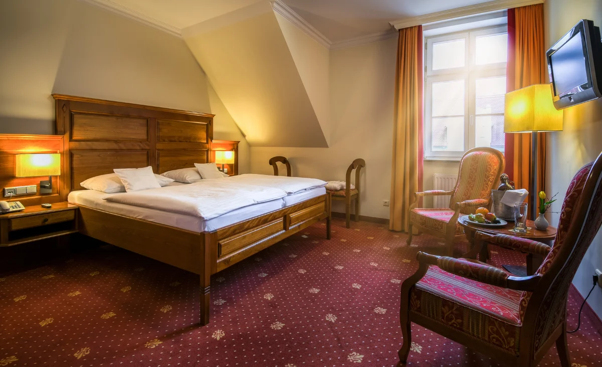 Gemütliches Hotelzimmer im Wasserschloss Mellenthin mit Bett, Stuhl und Fernseher.