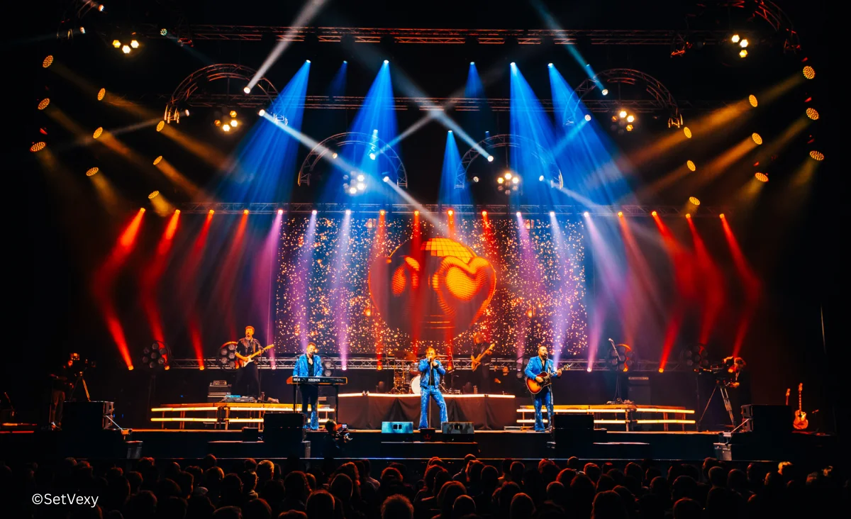 Eine Bühne mit Lichtern und Menschen während des Bee Gees Konzerts von Maincourse im Tempodrom Berlin.