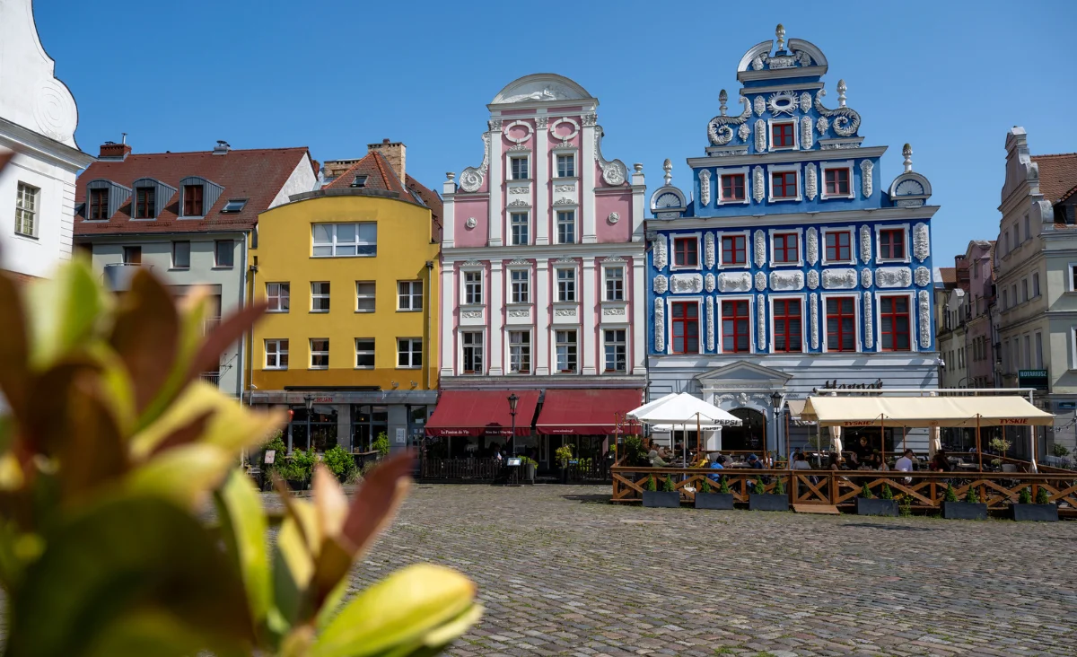 Menschen schlendern über die gepflasterten Straßen einer Stadt auf einer der deutschen Ostseeinseln, umgeben von historischen Gebäuden.