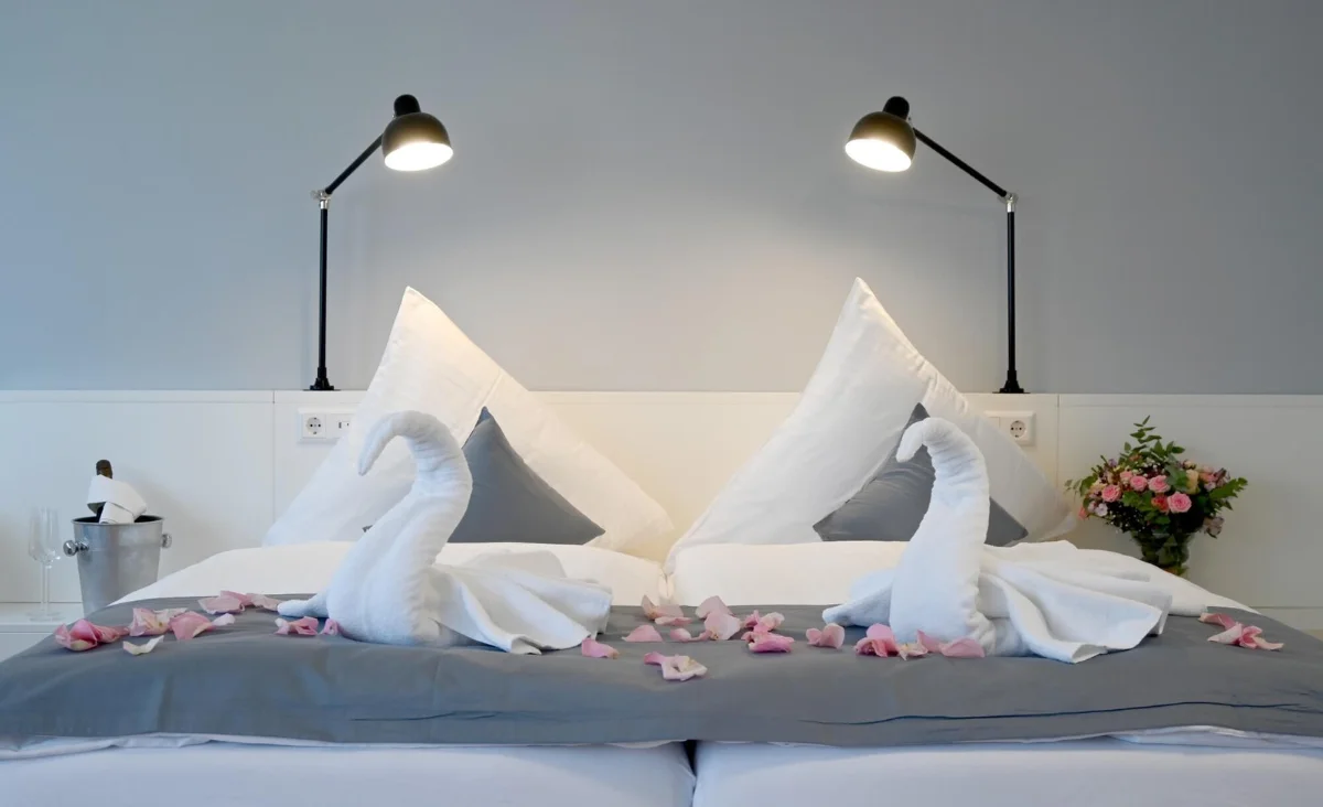 Zwei Schwäne liegen auf einem Bett mit weißen Bettlaken im Hotel Brandenburger Dom in Brandenburg an der Havel.
