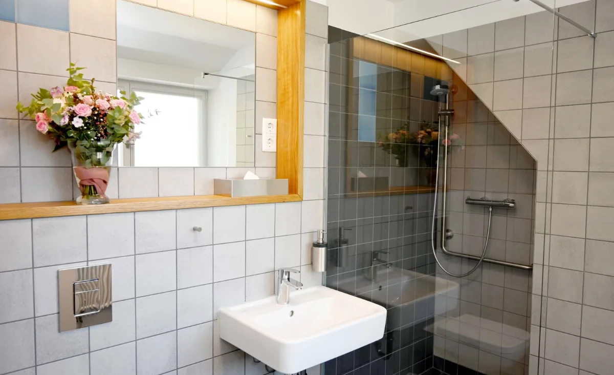 Badezimmer mit Waschbecken, Spiegel und Dusche im Hotel Brandenburger Dom in Brandenburg an der Havel.
