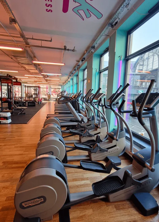 Innenansicht eines Fitnessstudios mit vielen Laufmaschinen und Fahrrädern