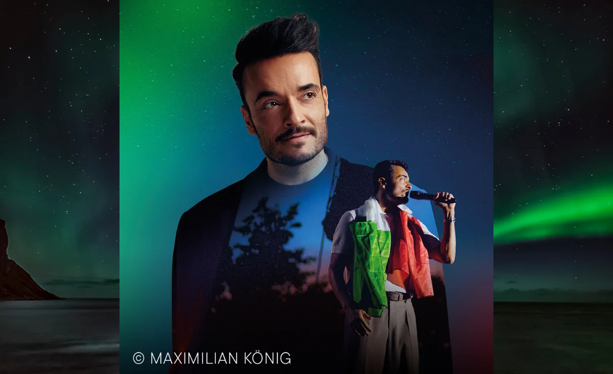 Giovanni Zarrella mit Mikrofon in der Hand und italienischer Flagge als Umhang bei Classic Open Air 2026 in Berlin vor einem Hintergrund mit Baum-Silhouette.