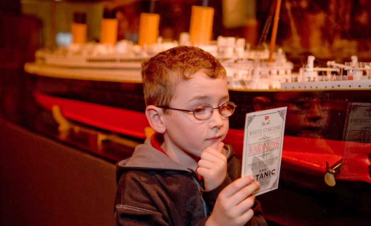 Ein junger Junge betrachtet ein Schiffsmodell und der Ticket der Titanic in der Ausstellung "Titanic - die Ausstellung".