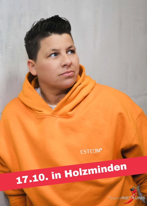 Kerstin Ott in einem orangefarbenen Hoodie lehnt entspannt gegen eine Wand bei der Veranstaltung 'SCHLAGERNACHT'26'.