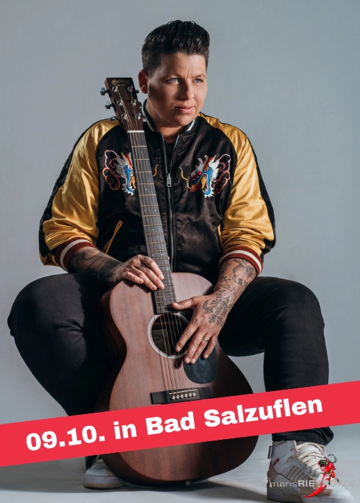 Kerstin Ott auf einem Stuhl mit akustischer Gitarre, Teil von SCHLAGERNACHT'26 mit Kerstin Ott.