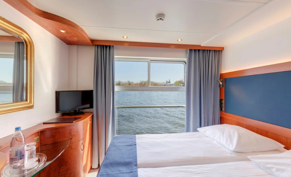 Gemütliches Schlafzimmer auf der MS Thurgau Saxonia mit Blick auf den Fluss bei der Flusskreuzfahrt Berlin Stettin.