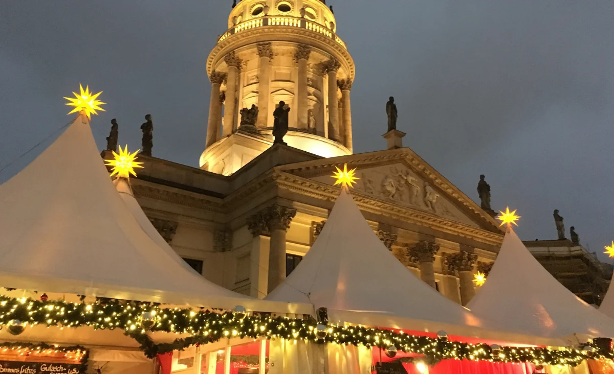 Weihnachtsmarkt am Gendarmenmarkt Berlin mit Zelten und Kirche im Hintergrund.
