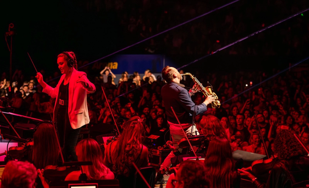 Saxophonspieler auf der Bühne, umgeben von einer jubelnden Menge bei der Synthony Europa Tour 2026.