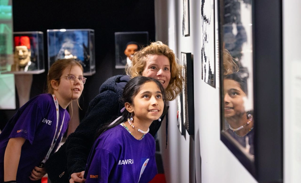 Drei Mädchen blicken interessiert auf eine Wand mit Ausstellungsstücken im Museum Bricks of Wonder Magdeburg